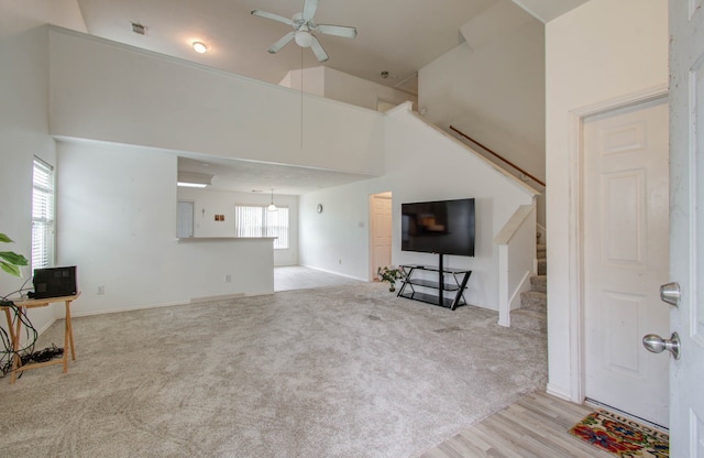 living room featuring light carpet, a towering ceiling, and ceiling fan