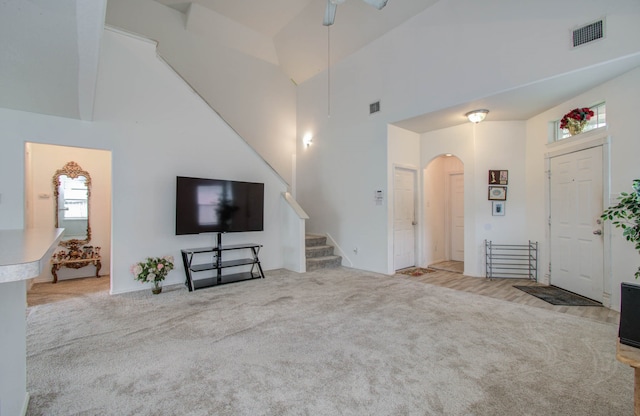 unfurnished living room with light carpet, high vaulted ceiling, and ceiling fan