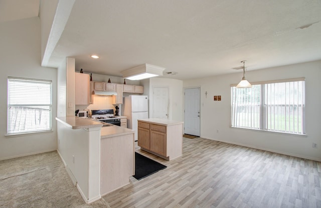 kitchen with white appliances, a healthy amount of sunlight, kitchen peninsula, and light brown cabinets