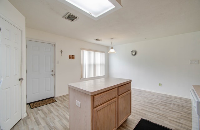 kitchen with decorative light fixtures, a kitchen island, and light wood-type flooring