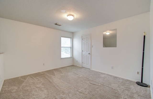 unfurnished room featuring a textured ceiling and light carpet