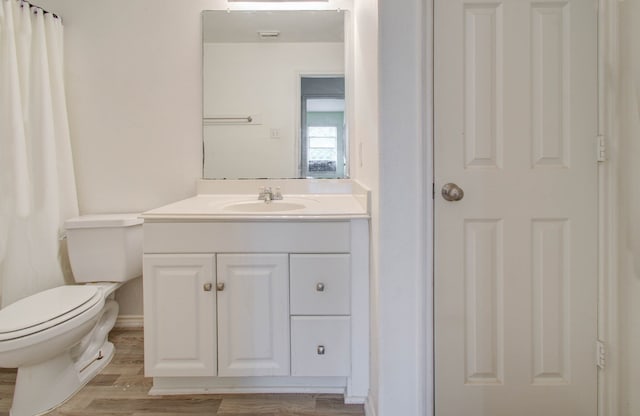 bathroom with wood-type flooring, toilet, and vanity