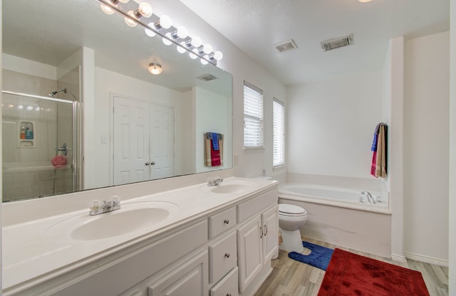 full bathroom featuring wood-type flooring, toilet, shower with separate bathtub, and vanity