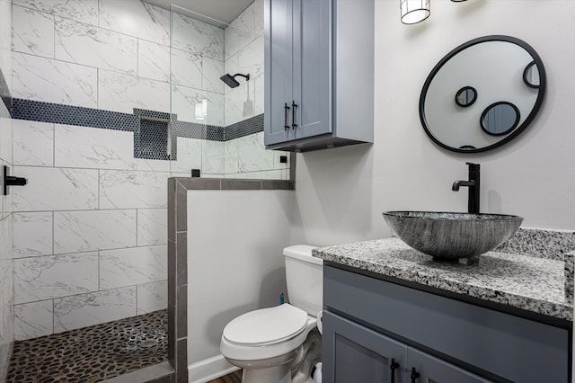 bathroom with vanity, toilet, and tiled shower