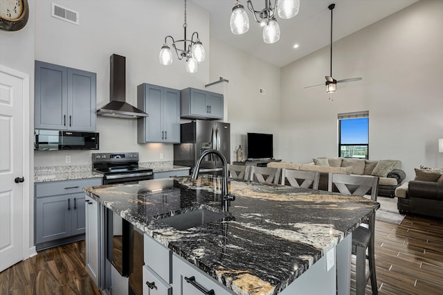 kitchen featuring sink, an island with sink, wall chimney exhaust hood, high vaulted ceiling, and appliances with stainless steel finishes