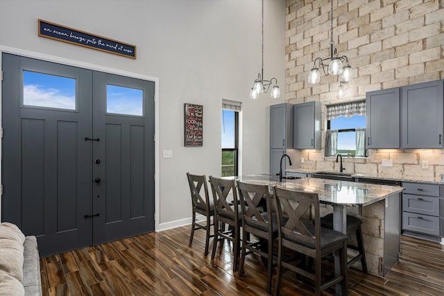 kitchen featuring pendant lighting, a center island, sink, a breakfast bar area, and light stone countertops