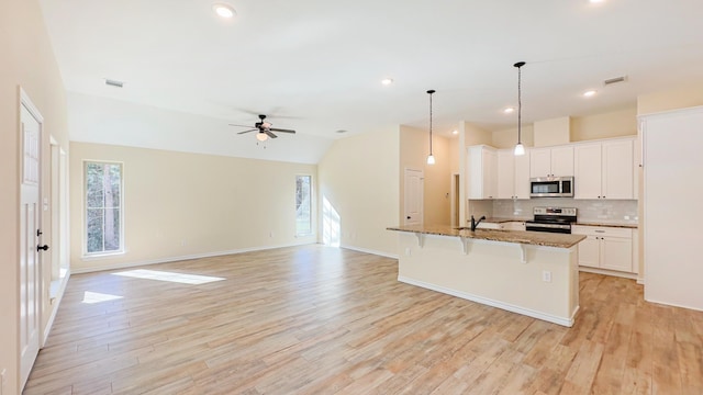 kitchen with white cabinetry, a breakfast bar area, ceiling fan, and stainless steel appliances