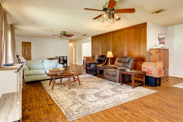 living room with a textured ceiling, wood-type flooring, and ceiling fan