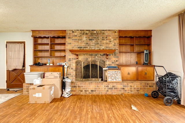 living room with a textured ceiling, light hardwood / wood-style flooring, and a brick fireplace