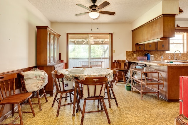 dining space featuring ceiling fan, a wealth of natural light, sink, and a textured ceiling