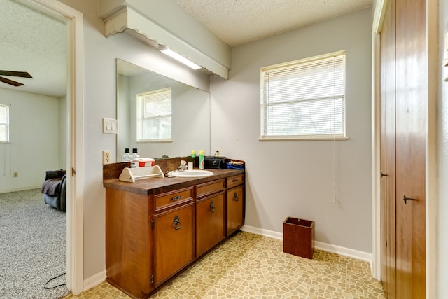 bathroom with a textured ceiling, vanity, and ceiling fan