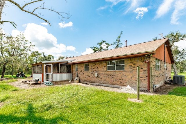 rear view of property with a sunroom, a lawn, and central air condition unit