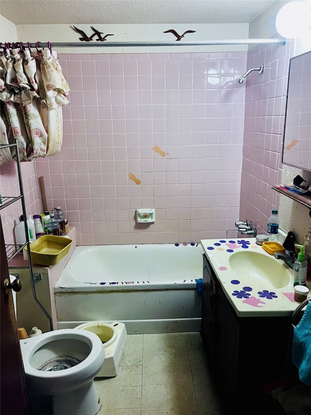 full bathroom with a textured ceiling, vanity, toilet, and tiled shower / bath