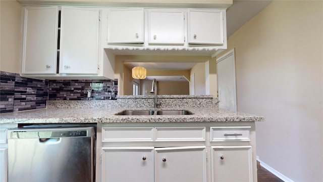 kitchen with light stone counters, dishwasher, sink, and white cabinets