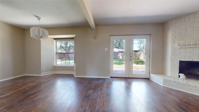 unfurnished living room with a fireplace, beamed ceiling, dark wood-type flooring, and french doors