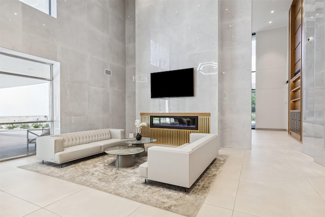 living room with a towering ceiling, a fireplace, tile walls, and light tile patterned flooring