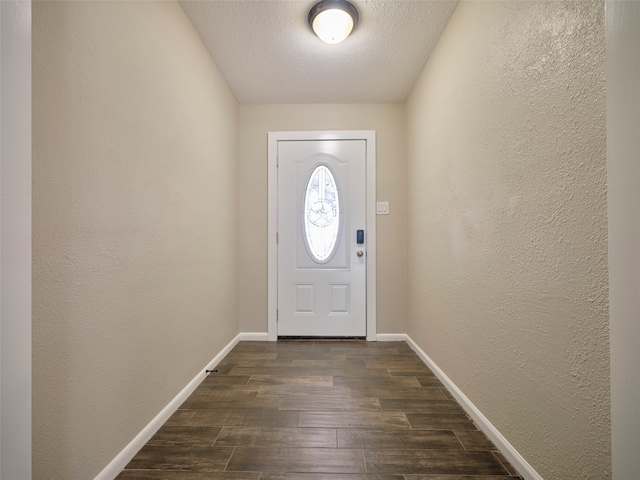 doorway with dark wood-type flooring and a textured ceiling