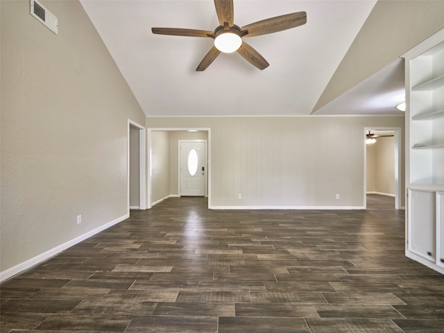 empty room featuring dark wood-type flooring, vaulted ceiling, ceiling fan, and wooden walls