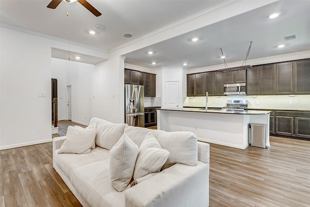 living room featuring light wood-type flooring, crown molding, sink, and ceiling fan