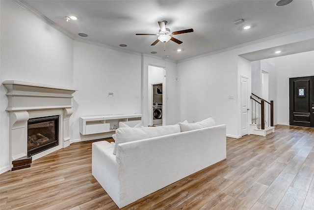 living room with light wood-type flooring, ceiling fan, washer / clothes dryer, and ornamental molding