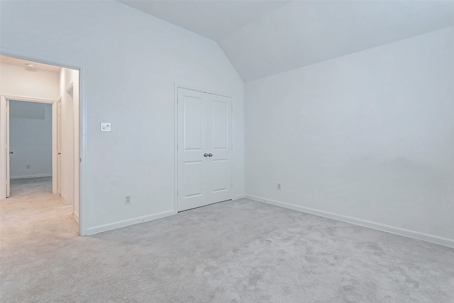 unfurnished bedroom featuring light carpet, lofted ceiling, and a closet