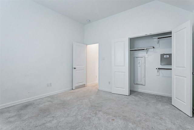 unfurnished bedroom featuring lofted ceiling, a closet, and light carpet