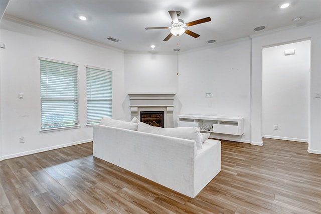 unfurnished living room with light wood-type flooring, ceiling fan, and ornamental molding