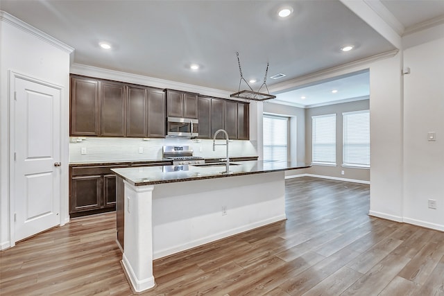 kitchen featuring light hardwood / wood-style flooring, appliances with stainless steel finishes, an island with sink, and sink