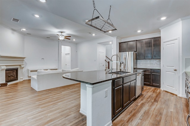 kitchen with a kitchen island with sink, light hardwood / wood-style flooring, stainless steel appliances, sink, and ceiling fan