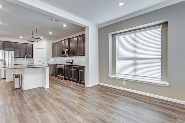 kitchen with an island with sink, a kitchen bar, stainless steel appliances, and light hardwood / wood-style floors