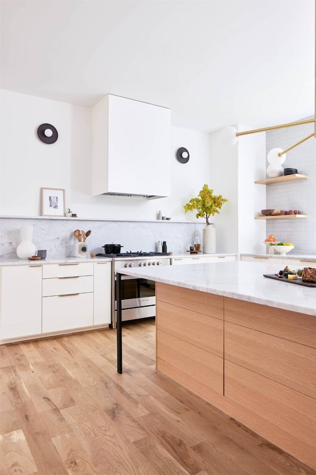 kitchen featuring light wood-type flooring, white cabinetry, and high end stainless steel range oven