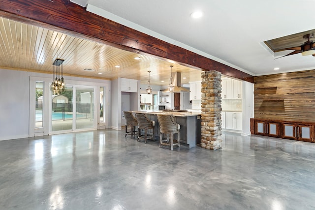 interior space with hanging light fixtures, white cabinetry, decorative columns, ceiling fan, and a breakfast bar