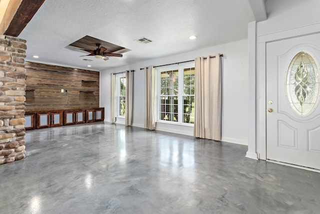 unfurnished living room featuring ceiling fan, wooden walls, and a textured ceiling