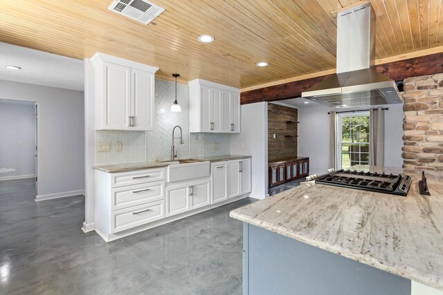 kitchen with island range hood, sink, light stone countertops, and stainless steel gas cooktop