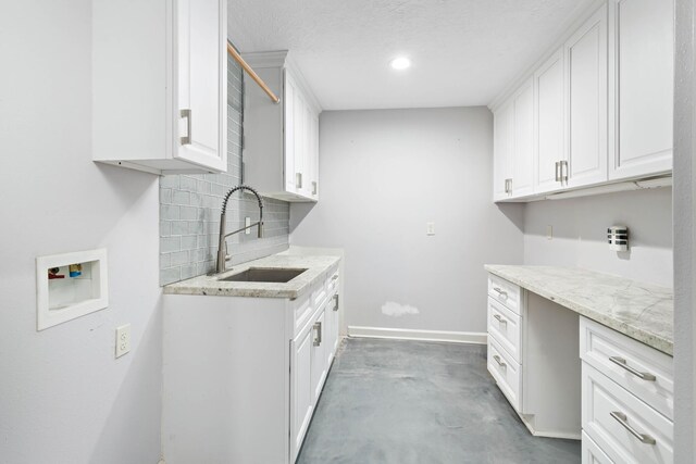 washroom featuring washer hookup, a textured ceiling, cabinets, and sink