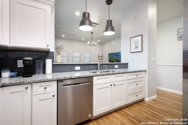 kitchen with tasteful backsplash, stainless steel dishwasher, white cabinets, and light hardwood / wood-style floors