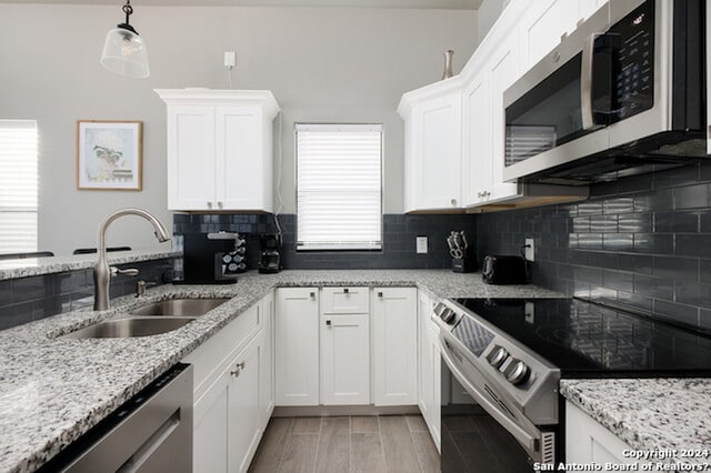 kitchen with appliances with stainless steel finishes, sink, decorative light fixtures, and white cabinets