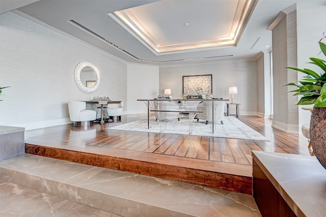 dining area featuring a raised ceiling, ornamental molding, and hardwood / wood-style flooring