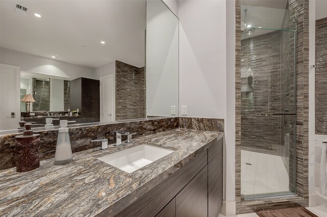 bathroom featuring a shower with door and vanity