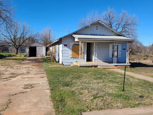 view of front of home with a front lawn, a shed, and covered porch