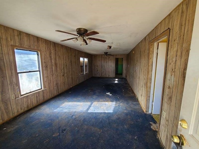 empty room with ceiling fan and wood walls