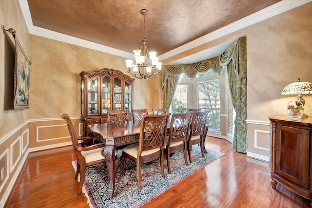 dining space featuring hardwood / wood-style floors, a chandelier, and ornamental molding