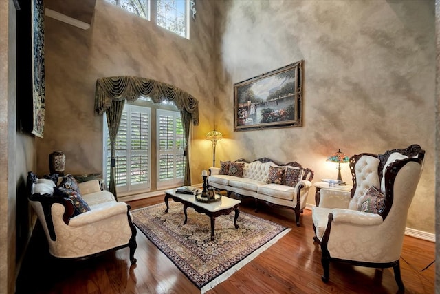 living room with plenty of natural light, a towering ceiling, and hardwood / wood-style floors