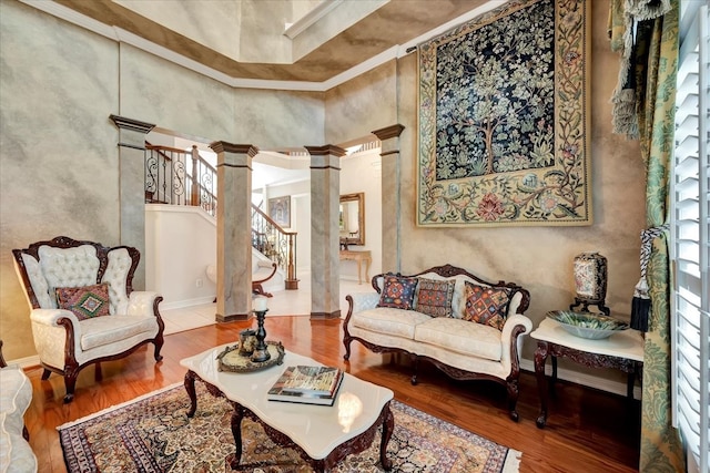 living room featuring a high ceiling, wood-type flooring, and decorative columns