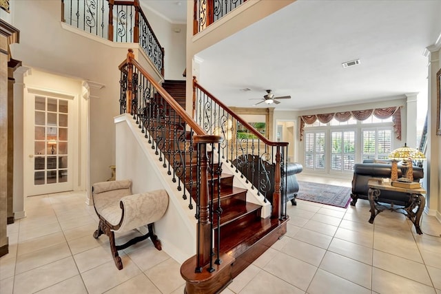 stairway with ceiling fan, crown molding, and tile patterned flooring