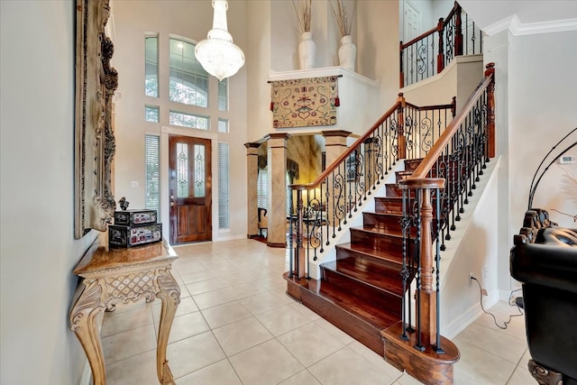 tiled foyer entrance with ornamental molding, an inviting chandelier, and a towering ceiling