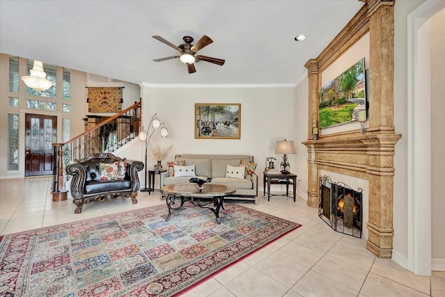 tiled living room featuring a fireplace, ornamental molding, and ceiling fan