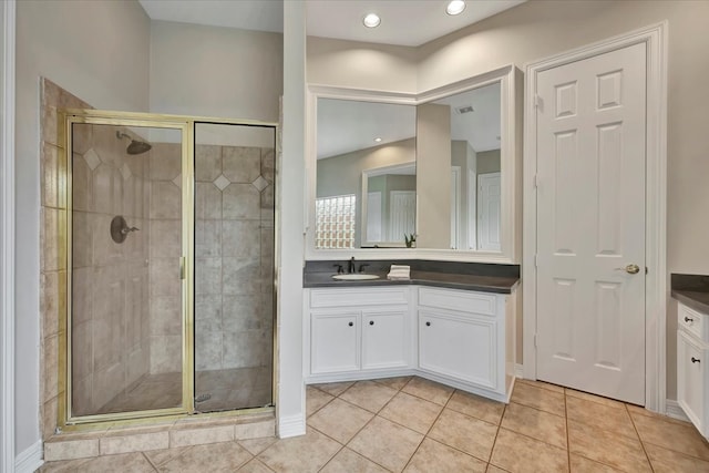 bathroom with tile patterned flooring, a shower with door, and vanity