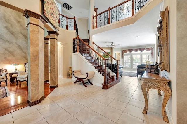 entryway featuring crown molding, ceiling fan, light tile patterned floors, and a high ceiling