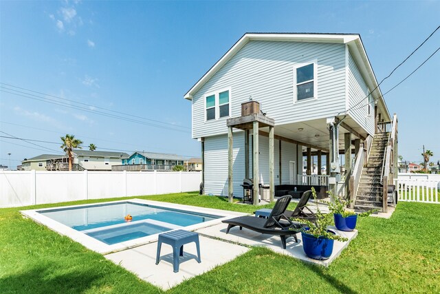 back of property with an in ground hot tub, a yard, and a patio